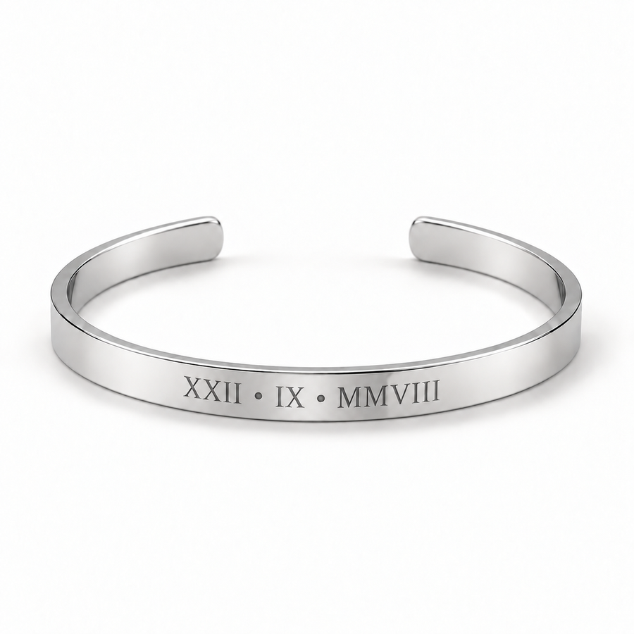A polished silver cuff bracelet with Roman numerals engraved on the front, displayed on a clean white background.