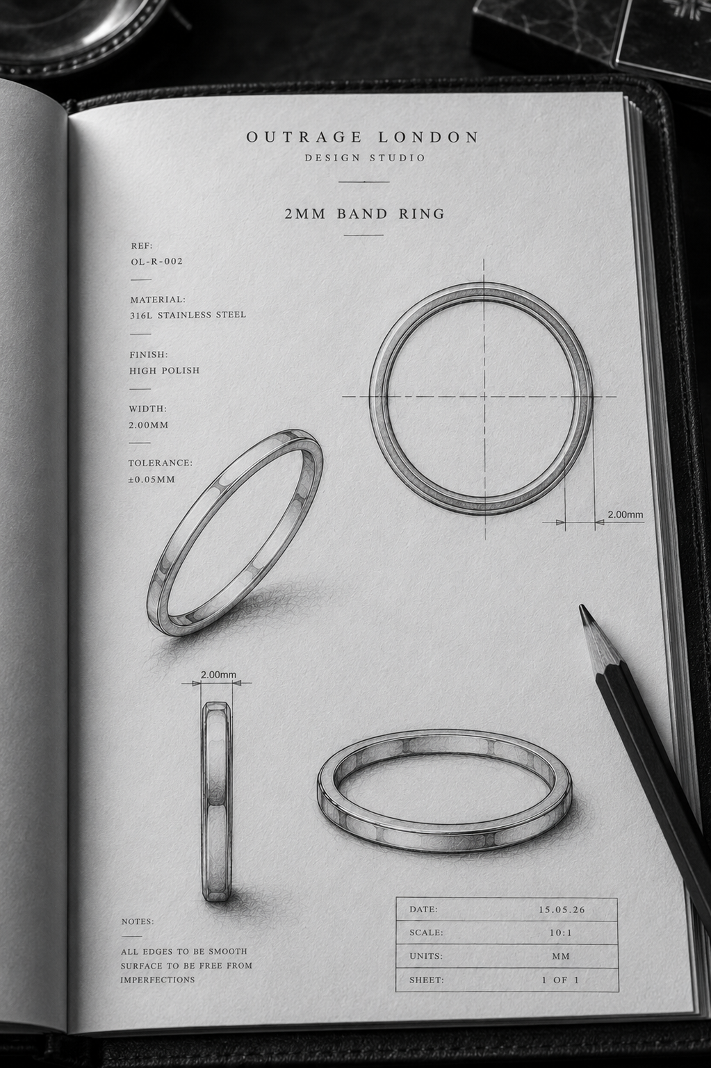 An open book or design journal page showing technical drawings and dimensions of a 2mm band ring by Outrage London Design Studio, with three ring views, measurement notes, and a pencil on a dark surface.