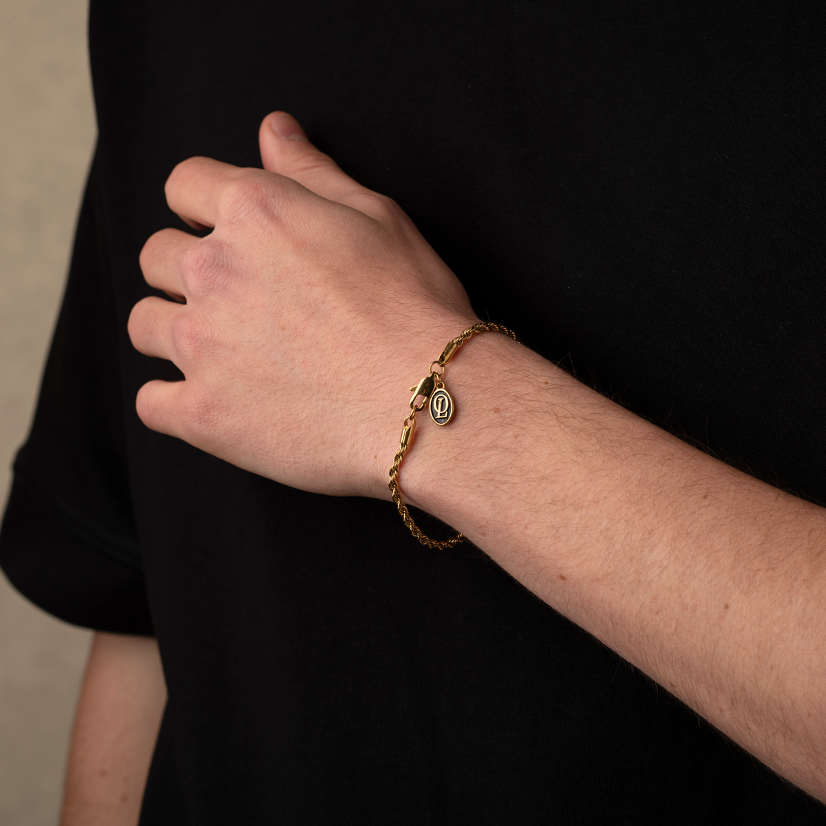 Hand wearing a gold bracelet with a dark background