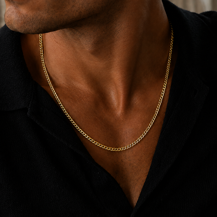 A close-up of a man's neck and chest wearing a gold chain necklace over a black shirt.