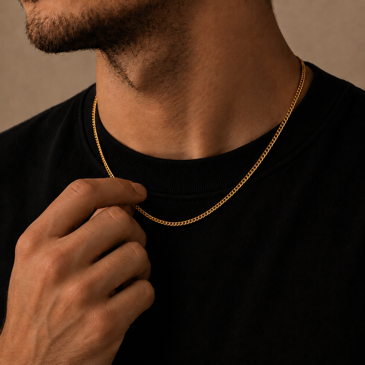 Close-up lifestyle image of a men’s 18k gold plated curb chain necklace, featuring a polished fine-link design worn over a black T-shirt and held gently by hand