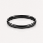 A minimalist matte black metal band ring, photographed from a top-down perspective on a clean white reflective surface.