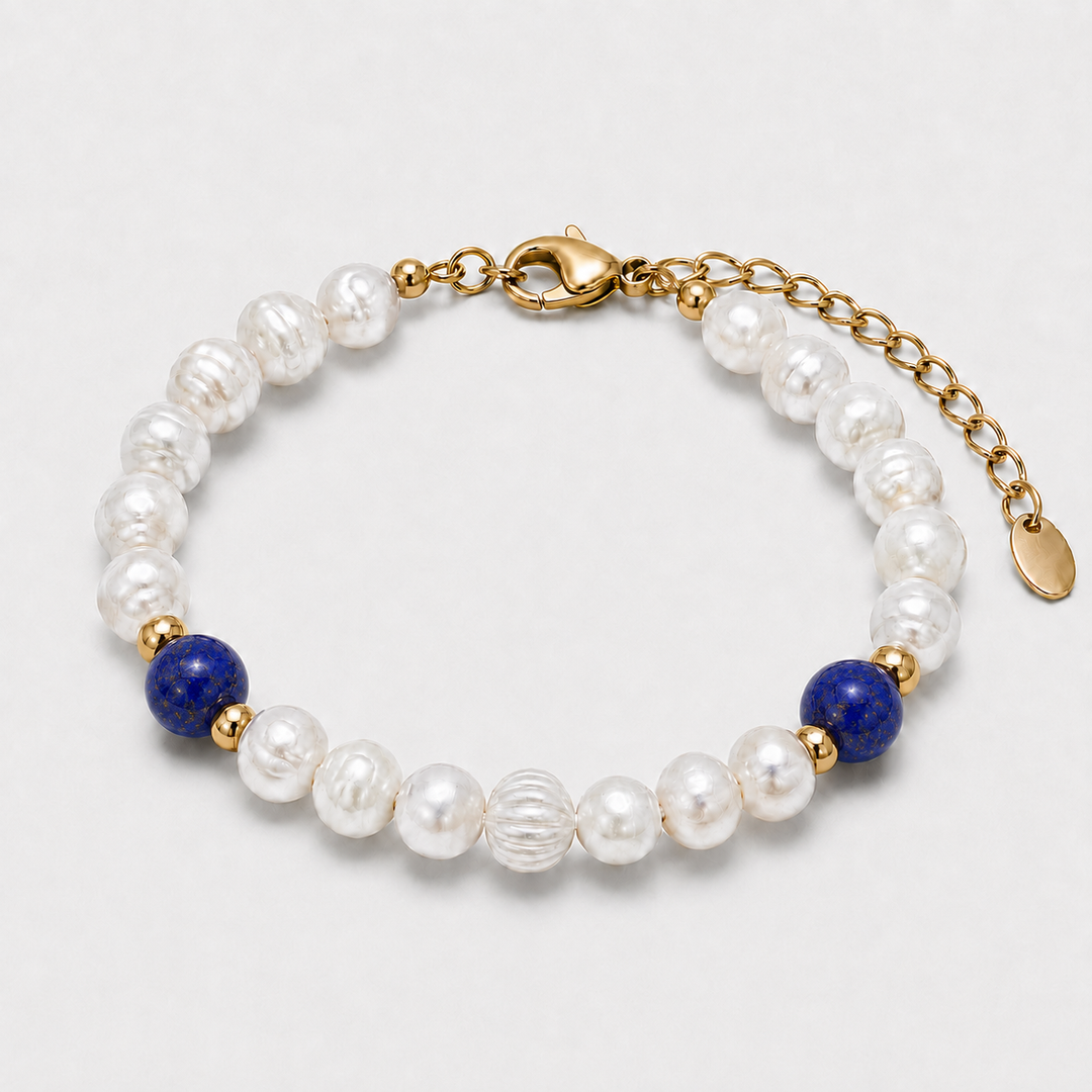 A beaded bracelet featuring white baroque pearls, two deep blue lapis lazuli stones, and gold spacer beads, finished with a gold lobster clasp and extension chain.