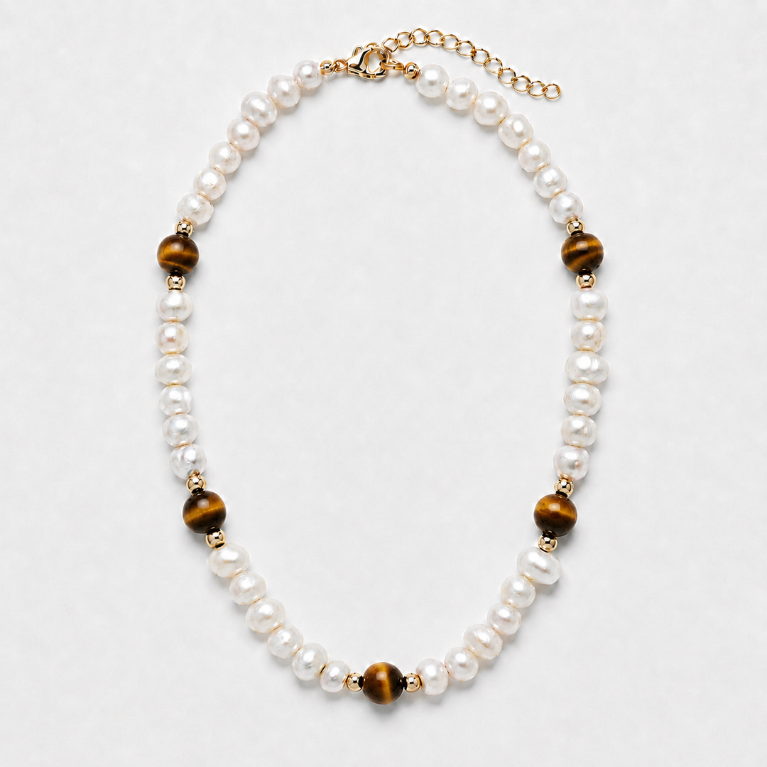 A pearl and tiger's eye bead necklace with gold-toned metal accents, displayed on a light gray background.