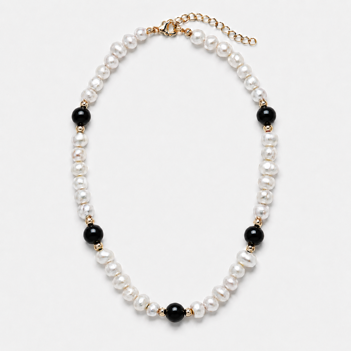 A pearl and black bead necklace with gold-tone metal accents, displayed on a clean white background.