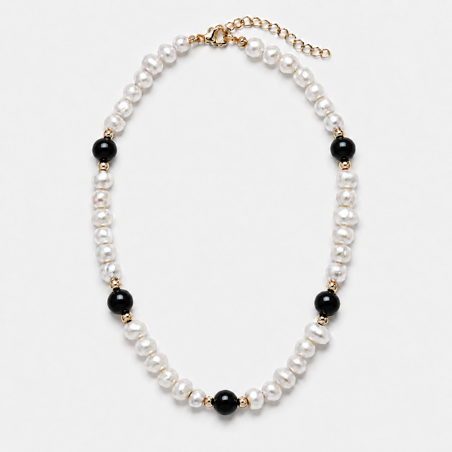 A pearl and black bead necklace with gold-tone metal accents, displayed on a clean white background.