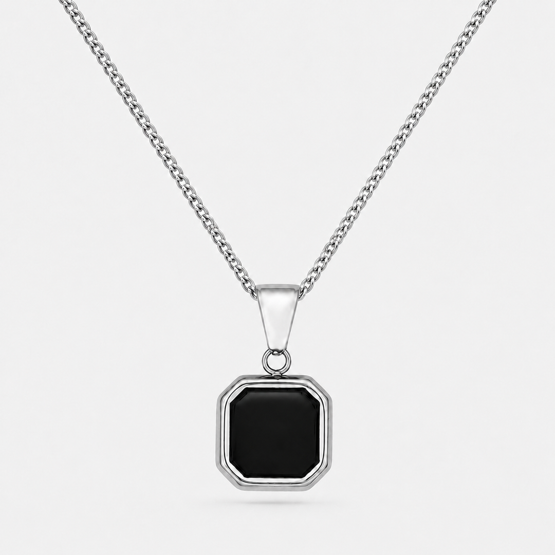 A silver-toned chain necklace with a geometric octagonal pendant featuring a black inlay, set against a light gray background.