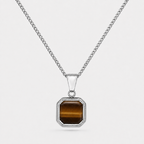 A silver-toned chain necklace with a square pendant featuring a brown tiger's eye stone, set against a light gray background.