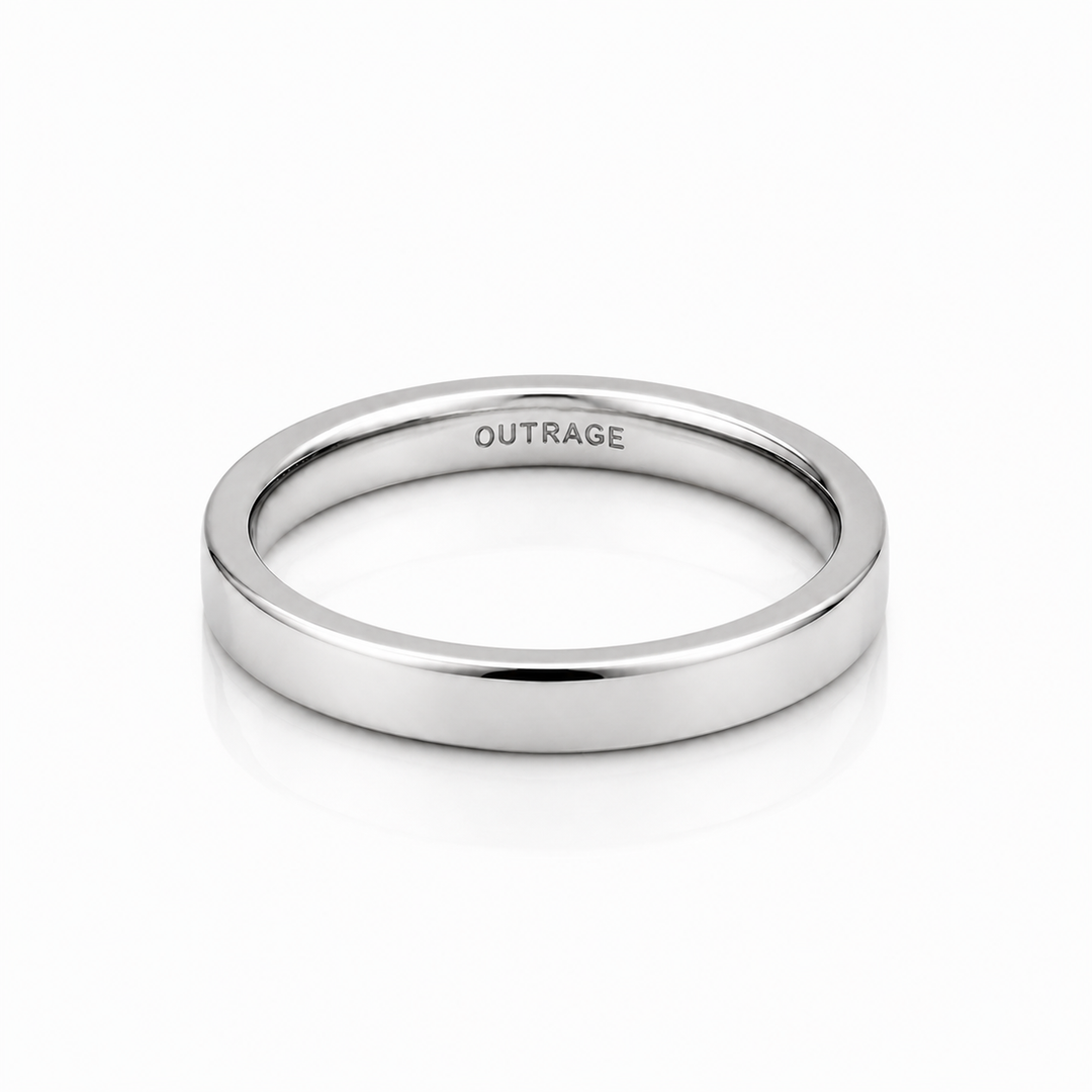 A minimalist, polished silver band ring with the word 'OUTRAGE' engraved inside, shown on a clean white background with a soft reflection.