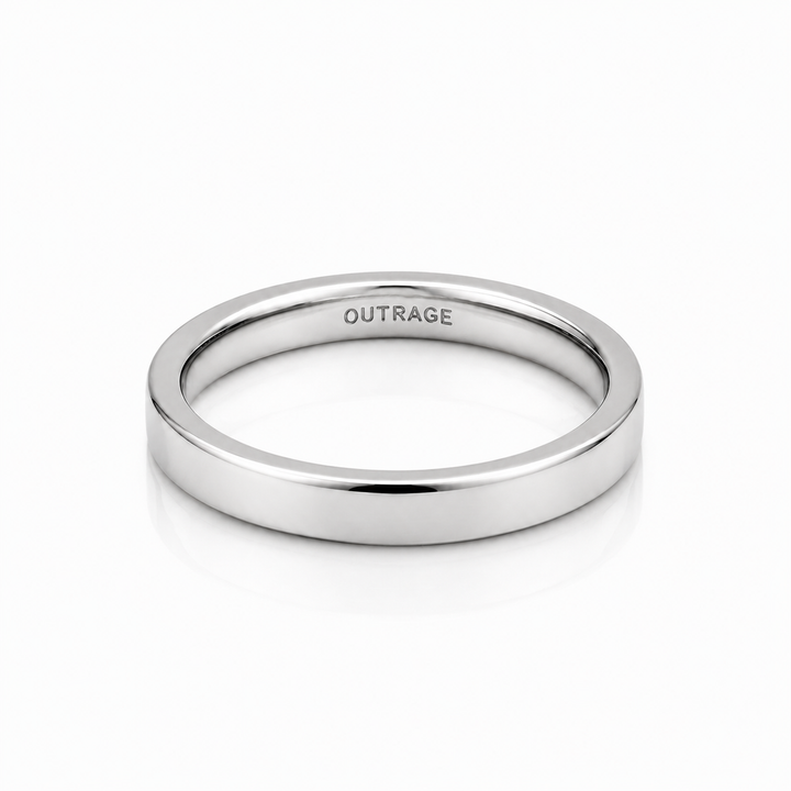 A minimalist, polished silver band ring with the word 'OUTRAGE' engraved inside, shown on a clean white background with a soft reflection.