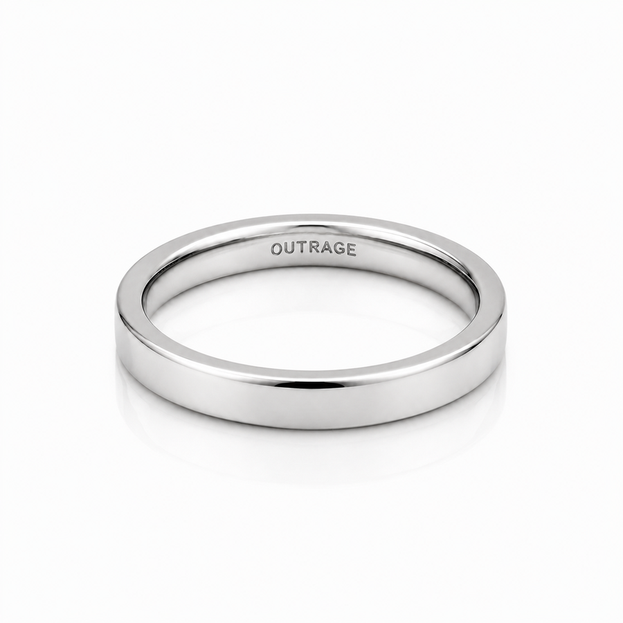 A minimalist, polished silver band ring with the word 'OUTRAGE' engraved inside, shown on a clean white background with a soft reflection.