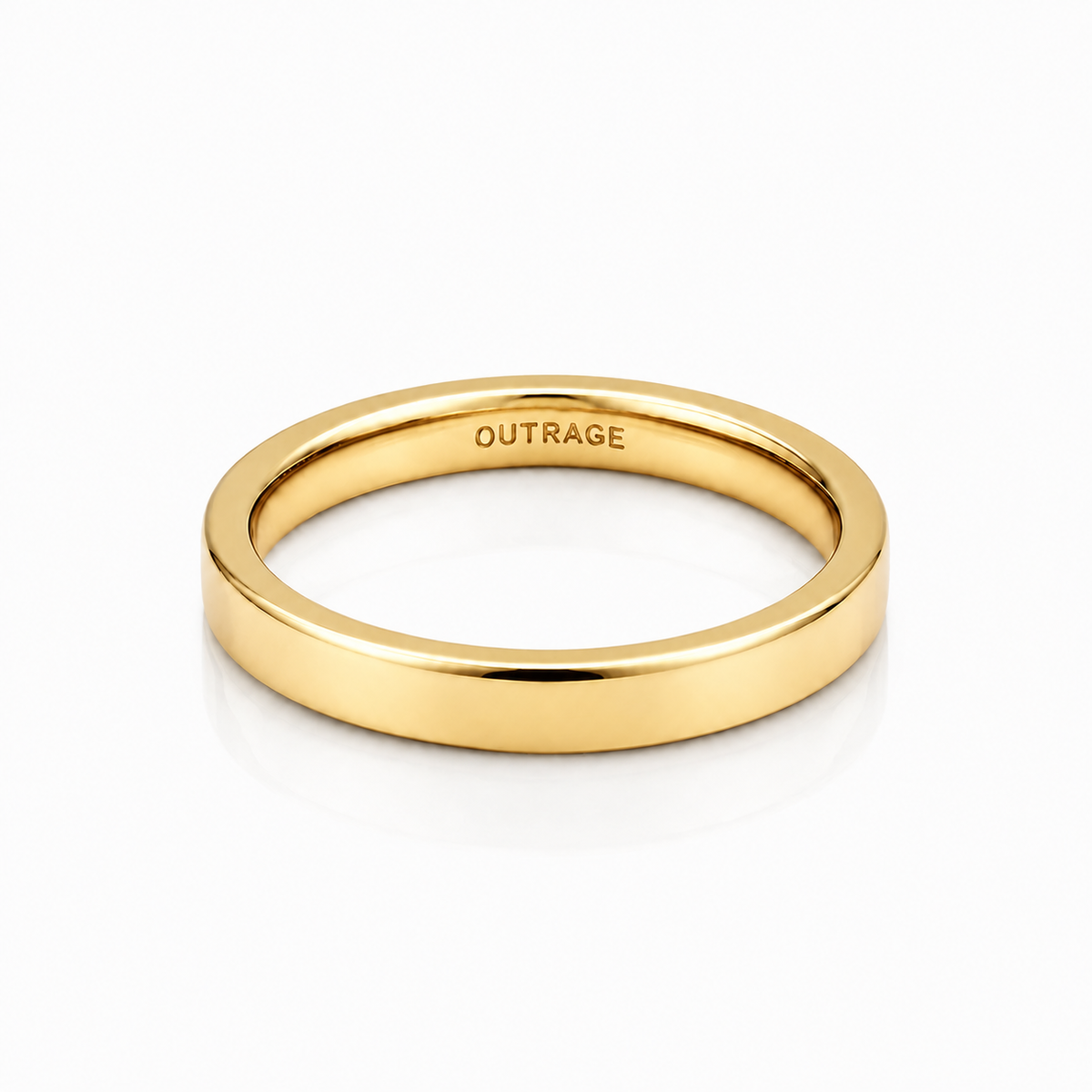 A polished yellow gold band ring with the word 'OUTRAGE' engraved inside, shown on a clean white background with a soft reflection.