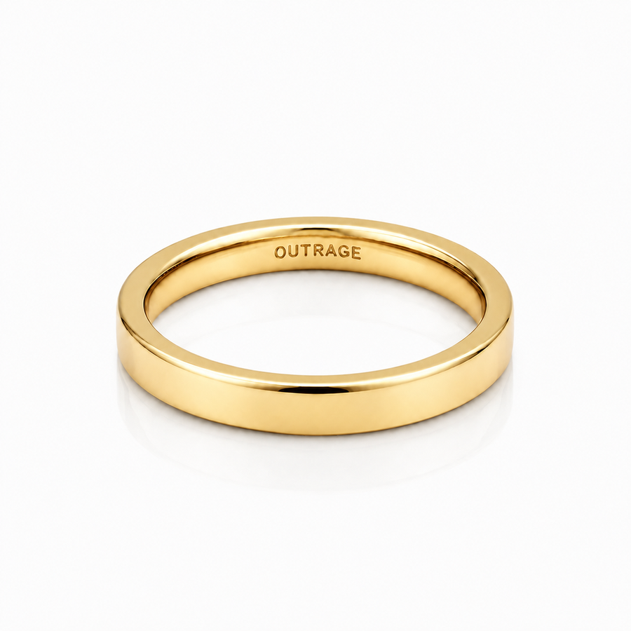 A polished yellow gold band ring with the word 'OUTRAGE' engraved inside, shown on a clean white background with a soft reflection.