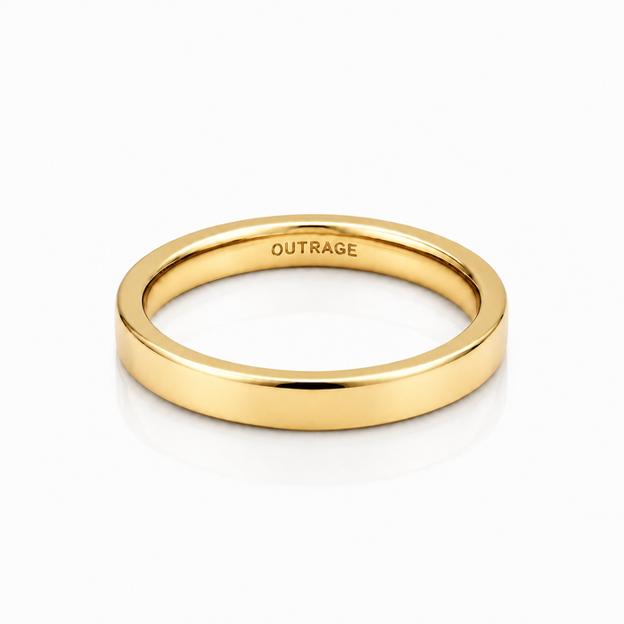 A polished yellow gold band ring with the word 'OUTRAGE' engraved inside, shown on a clean white background with a soft reflection.
