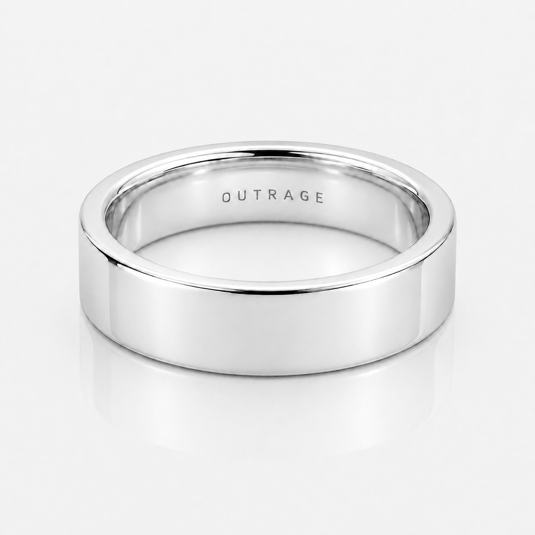 A polished silver band ring with the word 'OUTRAGE' engraved inside, shown on a clean white reflective surface.