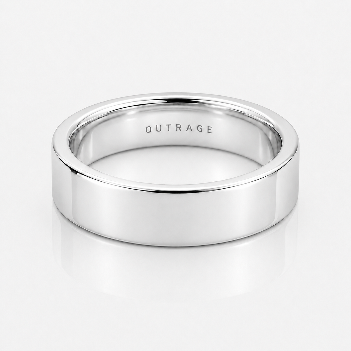 A polished silver band ring with the word 'OUTRAGE' engraved inside, shown on a clean white reflective surface.