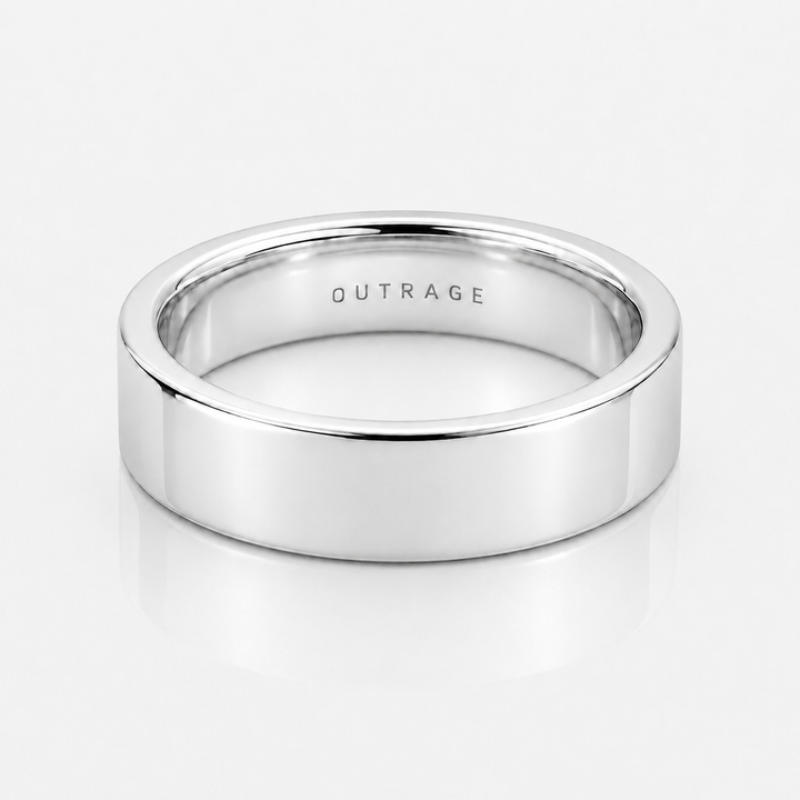 A polished silver band ring with the word 'OUTRAGE' engraved inside, shown on a clean white reflective surface.
