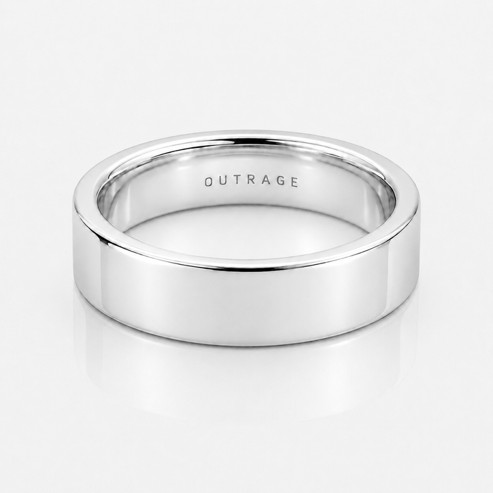 A polished silver band ring with the word 'OUTRAGE' engraved inside, shown on a clean white reflective surface.
