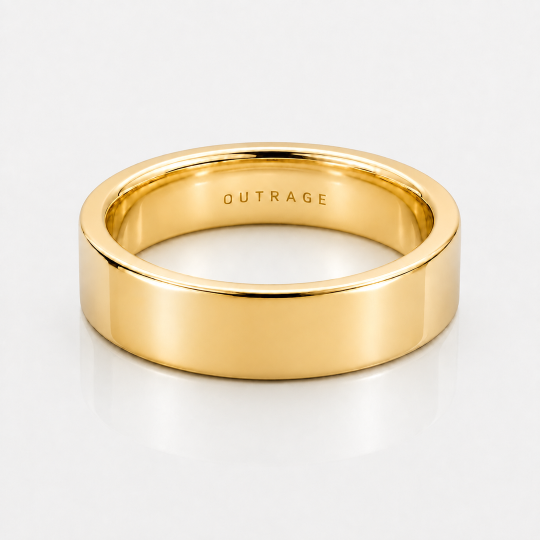 A polished yellow gold band ring with the word 'OUTRAGE' engraved inside, shown on a clean white background.