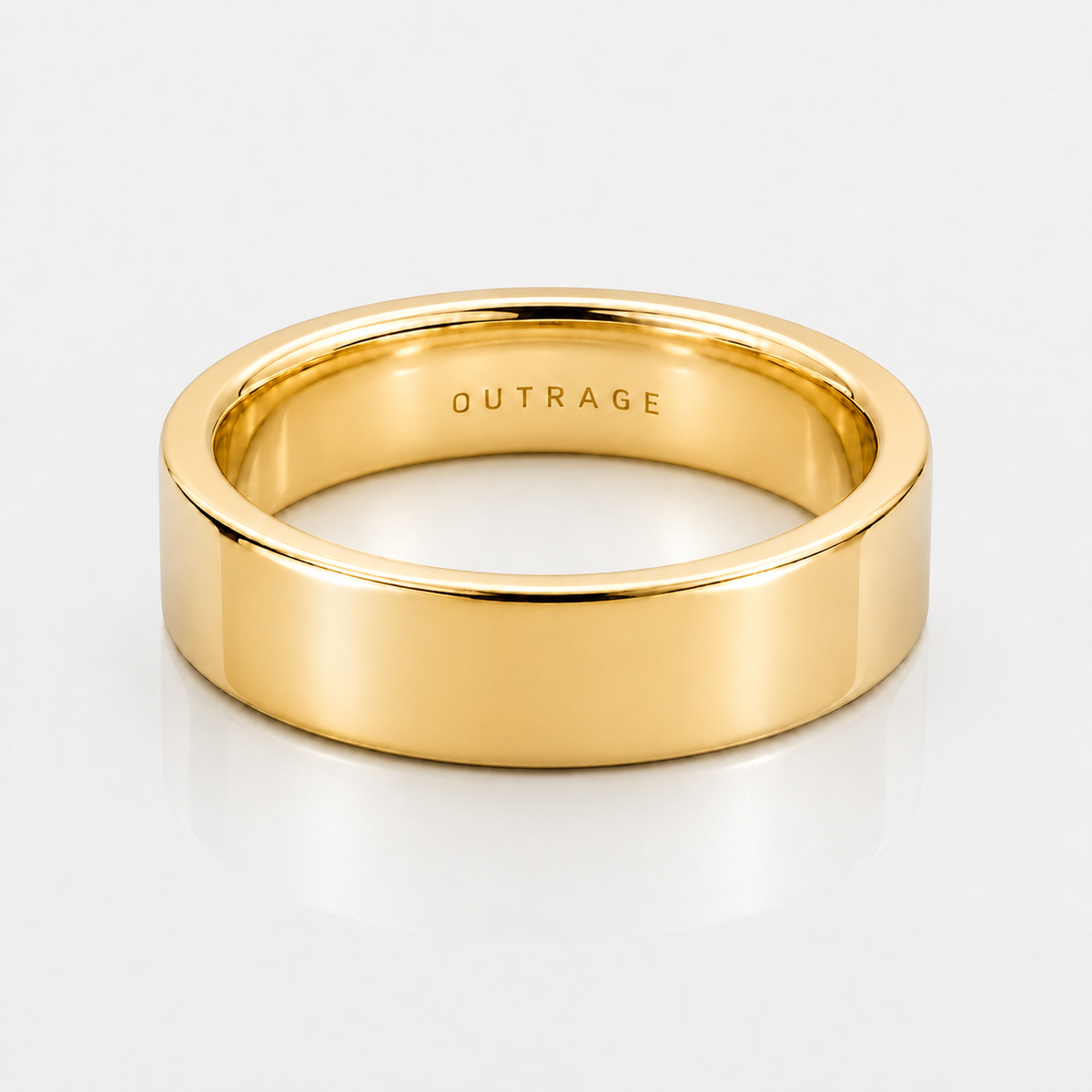 A polished yellow gold band ring with the word 'OUTRAGE' engraved inside, shown on a clean white background.