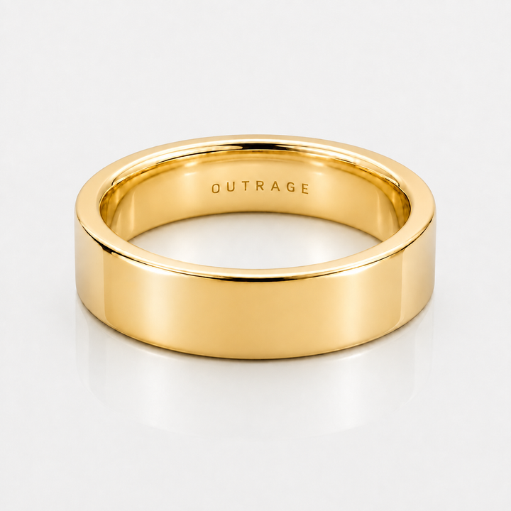 A polished yellow gold band ring with the word 'OUTRAGE' engraved inside, shown on a clean white background.