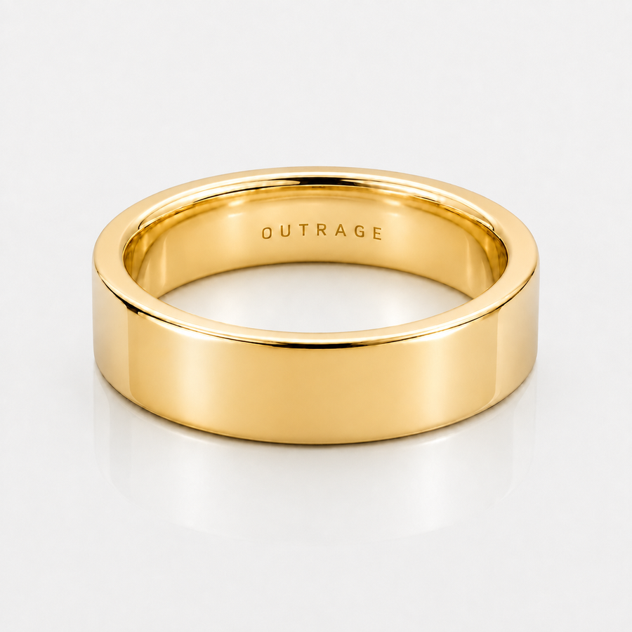 A polished yellow gold band ring with the word 'OUTRAGE' engraved inside, shown on a clean white background.