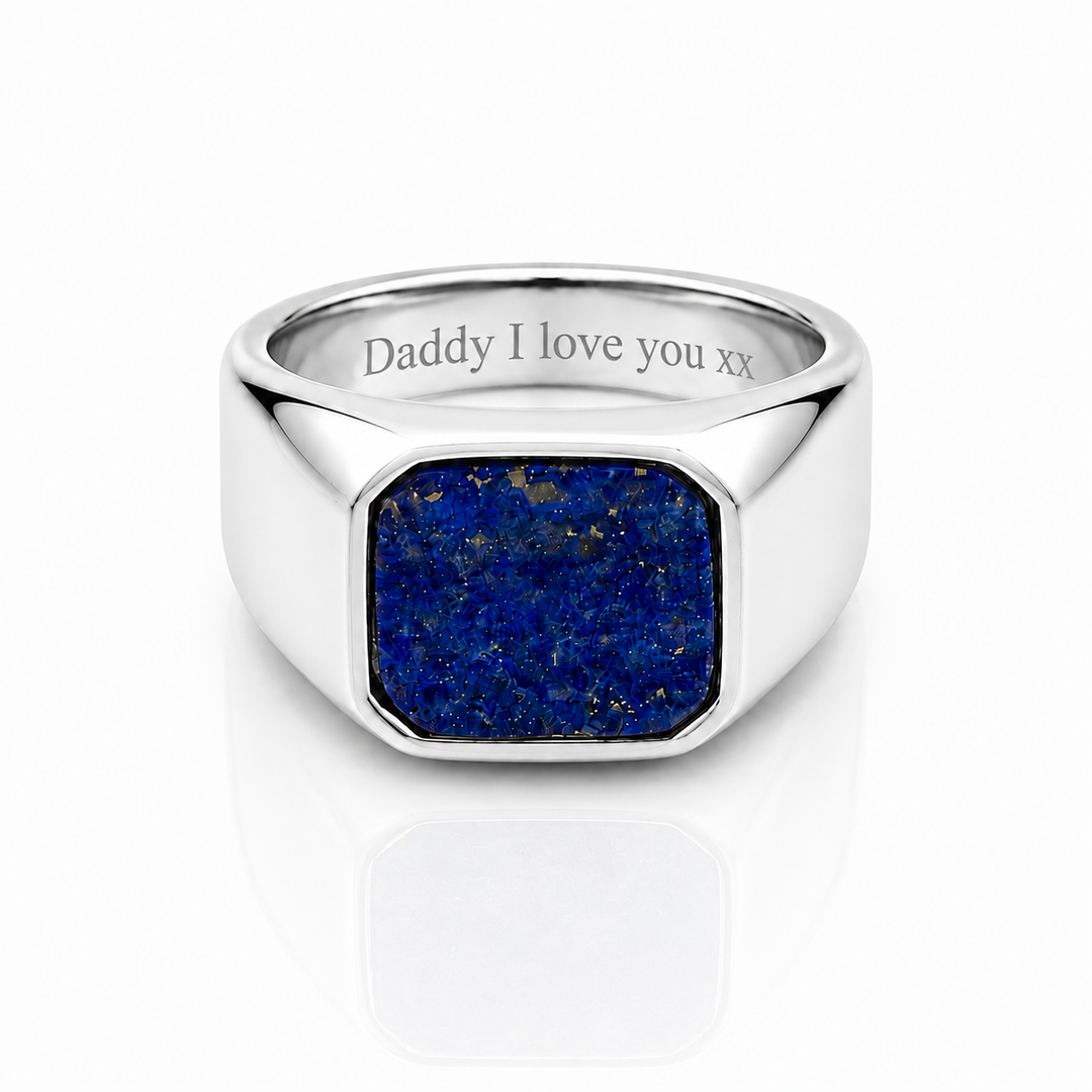 A silver signet ring featuring a square blue lapis lazuli stone face, with 'Daddy I love you xx' engraved on the inside band, set against a clean white background with a soft reflection.