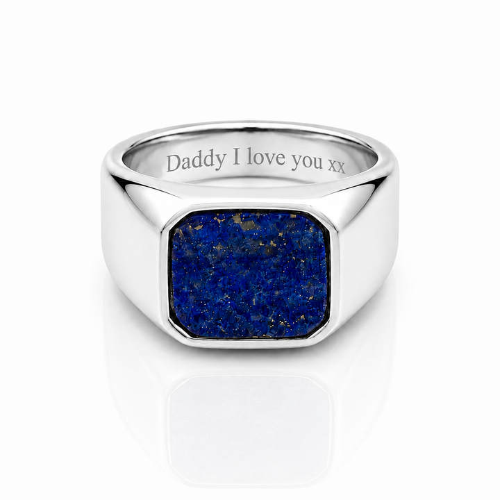 A silver signet ring featuring a square blue lapis lazuli stone face, with 'Daddy I love you xx' engraved on the inside band, set against a clean white background with a soft reflection.