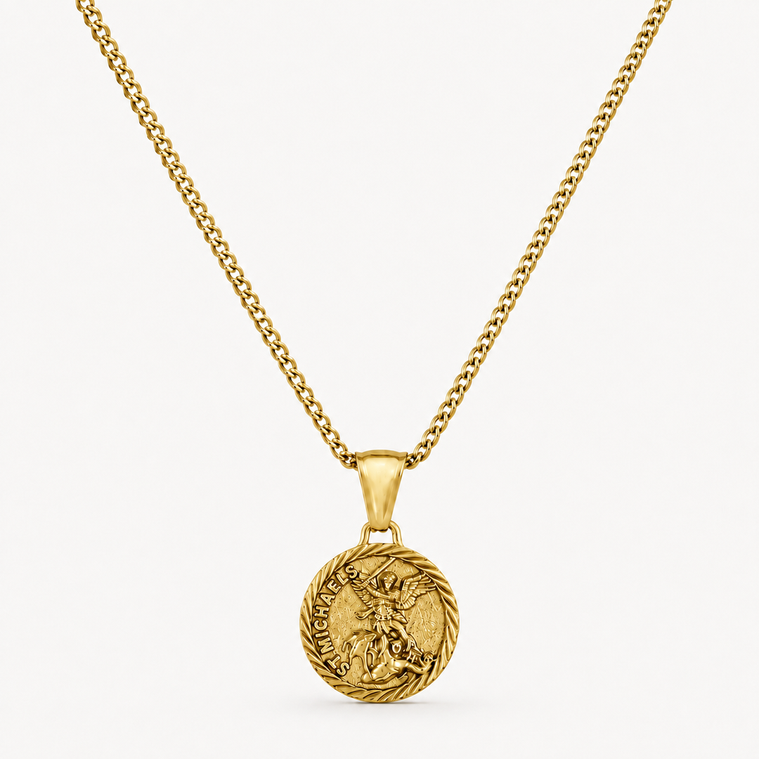 A gold chain necklace with a round medallion pendant featuring a detailed figure and engraved text, displayed against a clean off-white background.