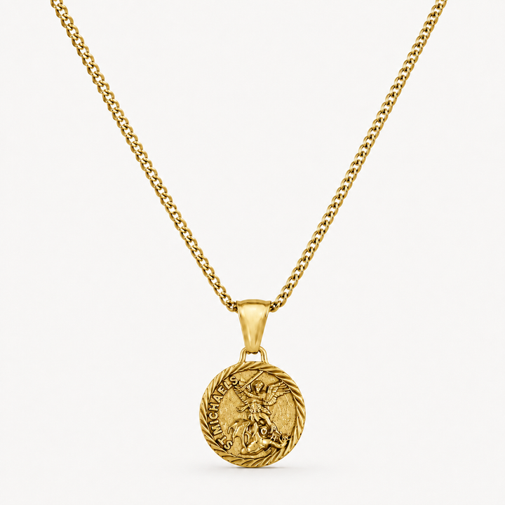 A gold chain necklace with a round medallion pendant featuring a detailed figure and engraved text, displayed against a clean off-white background.