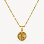 A gold chain necklace with a round medallion pendant featuring a detailed figure and engraved text, displayed against a clean off-white background.