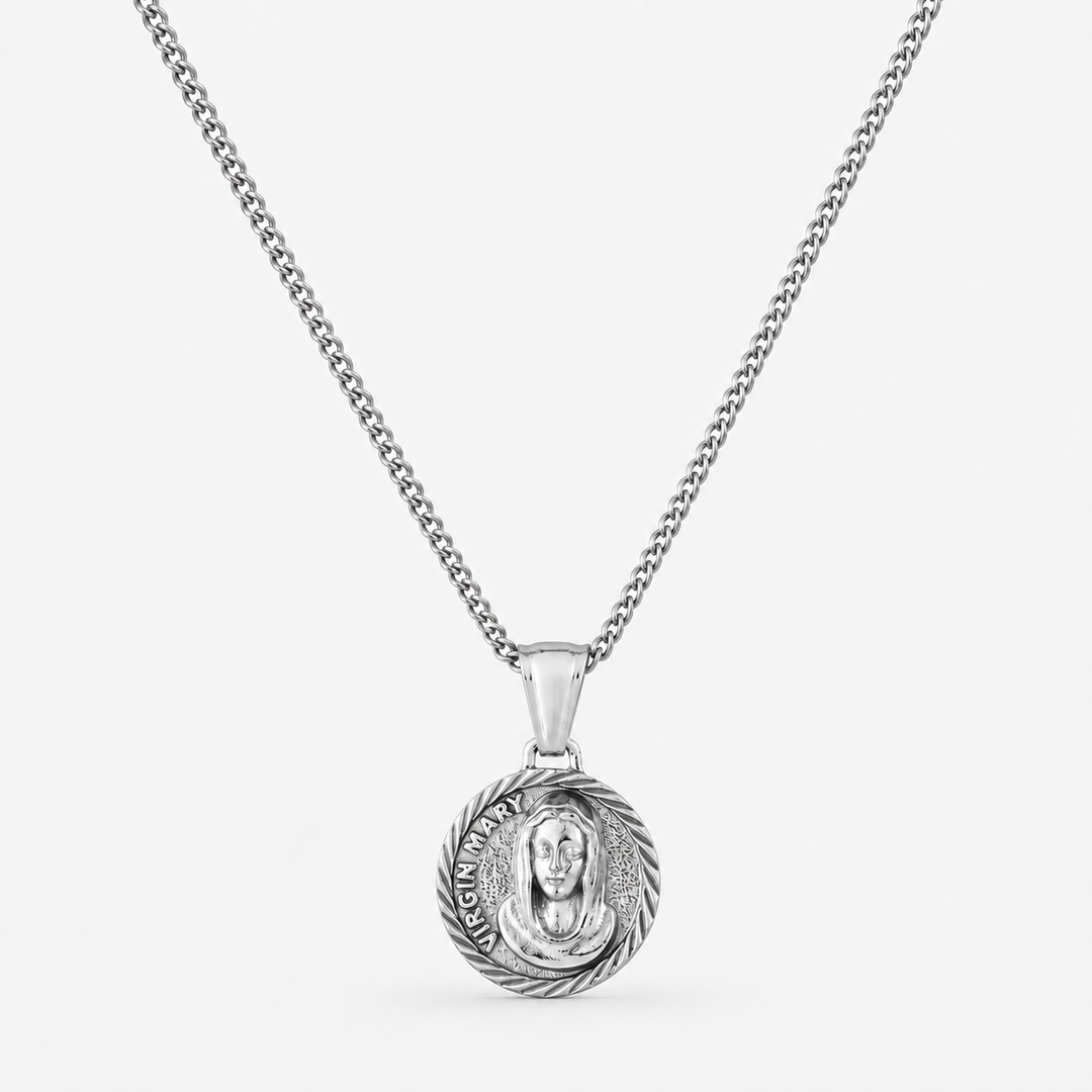 A silver chain necklace with a round pendant featuring a detailed religious medallion, shown against a plain light gray background.