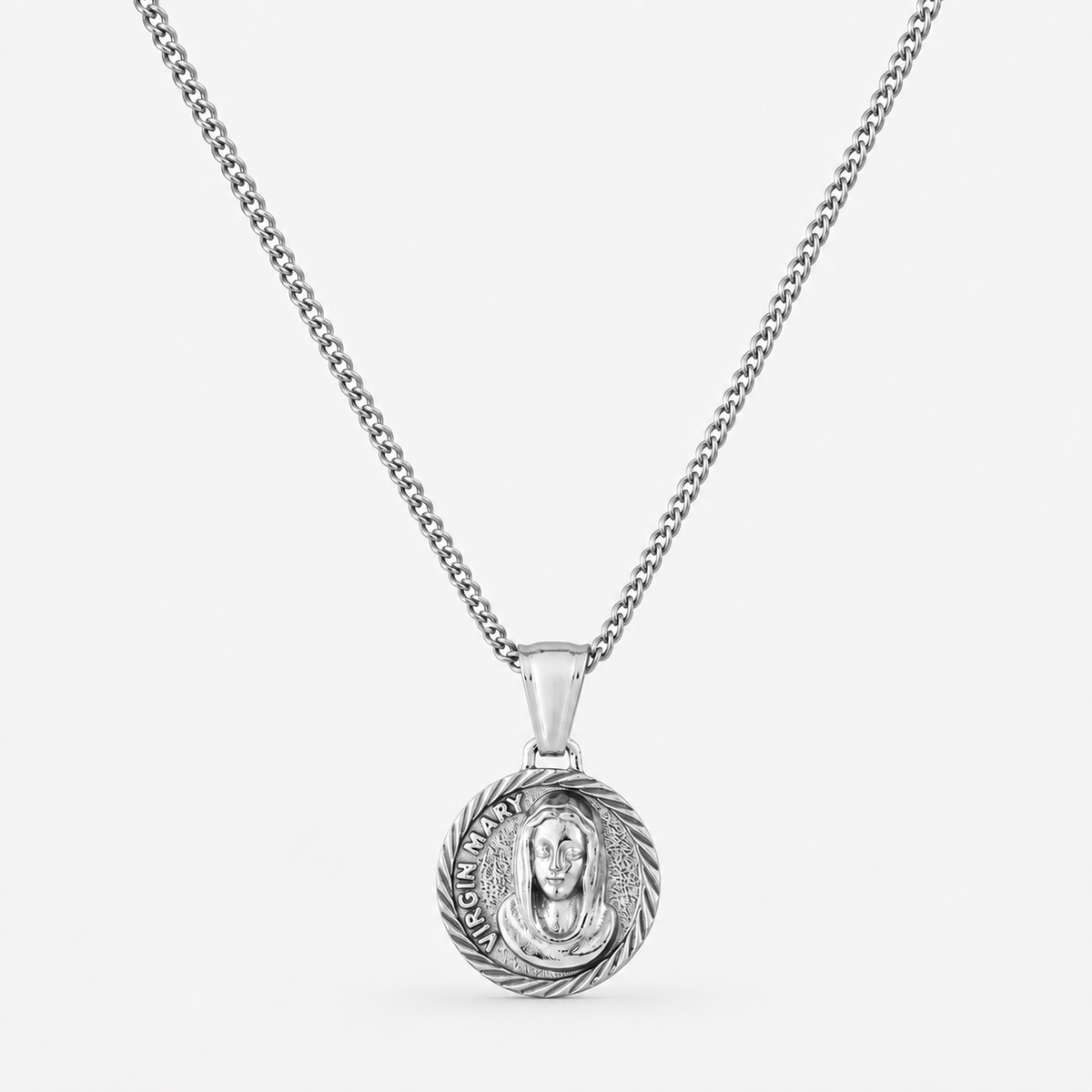 A silver chain necklace with a round pendant featuring a detailed religious medallion, shown against a plain light gray background.