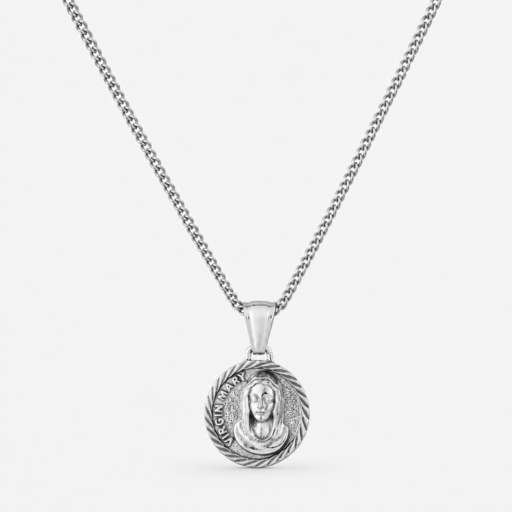 A silver chain necklace with a round pendant featuring a detailed religious medallion, shown against a plain light gray background.