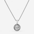 A silver chain necklace with a round pendant featuring a detailed religious medallion, shown against a plain light gray background.