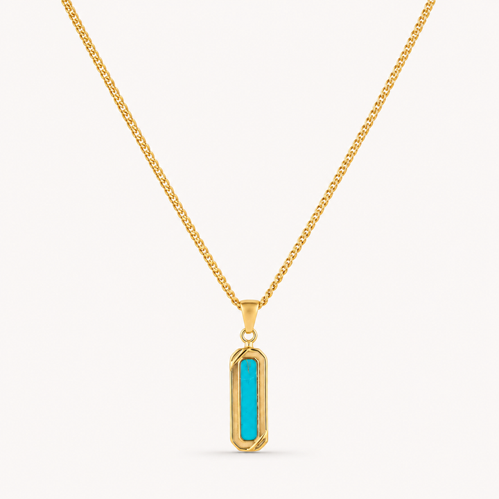 A gold chain necklace with a vertical bar pendant featuring a bright turquoise center, set against a plain off-white background.