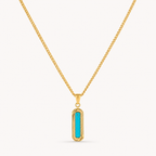 A gold chain necklace with a vertical bar pendant featuring a bright turquoise center, set against a plain off-white background.