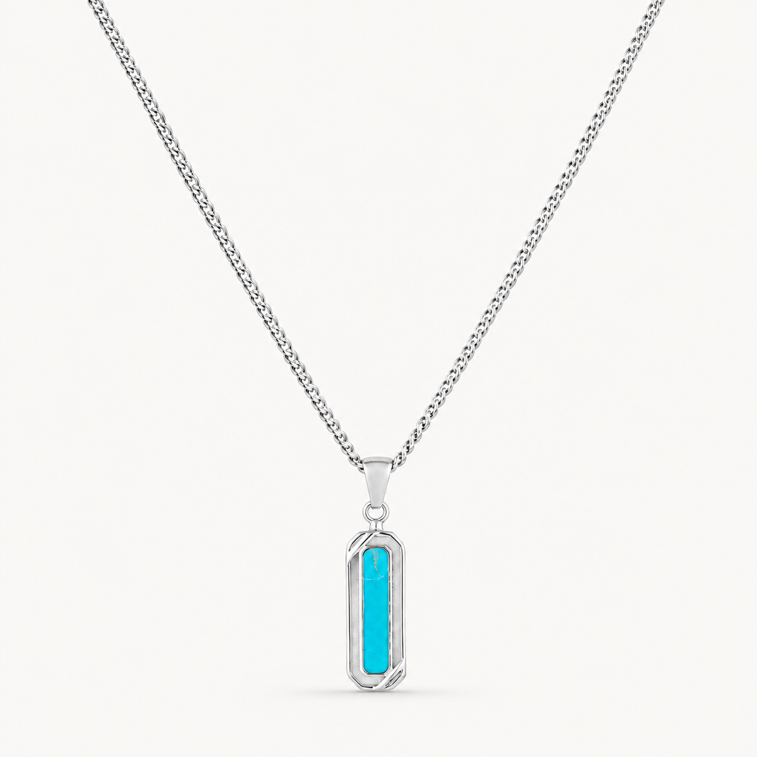 A silver-toned chain necklace with a vertical rectangular pendant featuring a bright turquoise blue center, shown on a clean off-white background.