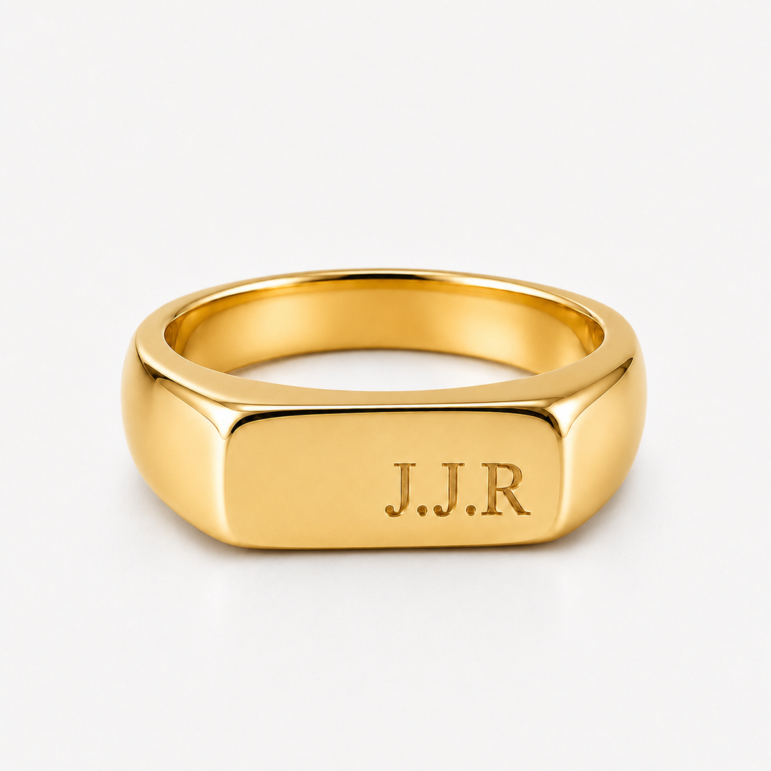 A polished yellow gold signet ring with the initials 'J.J.R' engraved on the face, shown on a clean white background.