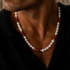 A close-up of a man wearing a beaded necklace with white pearls, dark red beads, and small gold spacer beads, paired with a black shirt.
