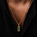A gold chain necklace with a vertical rectangular pendant featuring a green textured inlay, worn by a person in a black shirt.