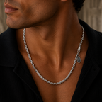 A close-up of a man wearing a silver twisted rope chain necklace with a small oval charm, styled with a black collared shirt.