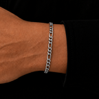 A close-up of a person's wrist wearing a silver-toned curb link chain bracelet, set against a dark black shirt background.