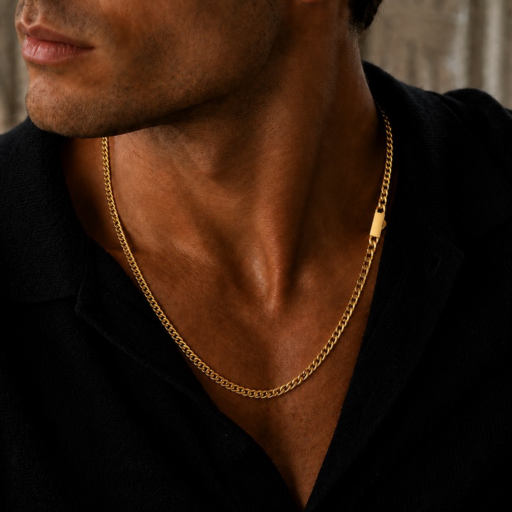 A close-up of a man wearing a polished yellow gold chain necklace with a simple rectangular tag, styled with a black shirt.