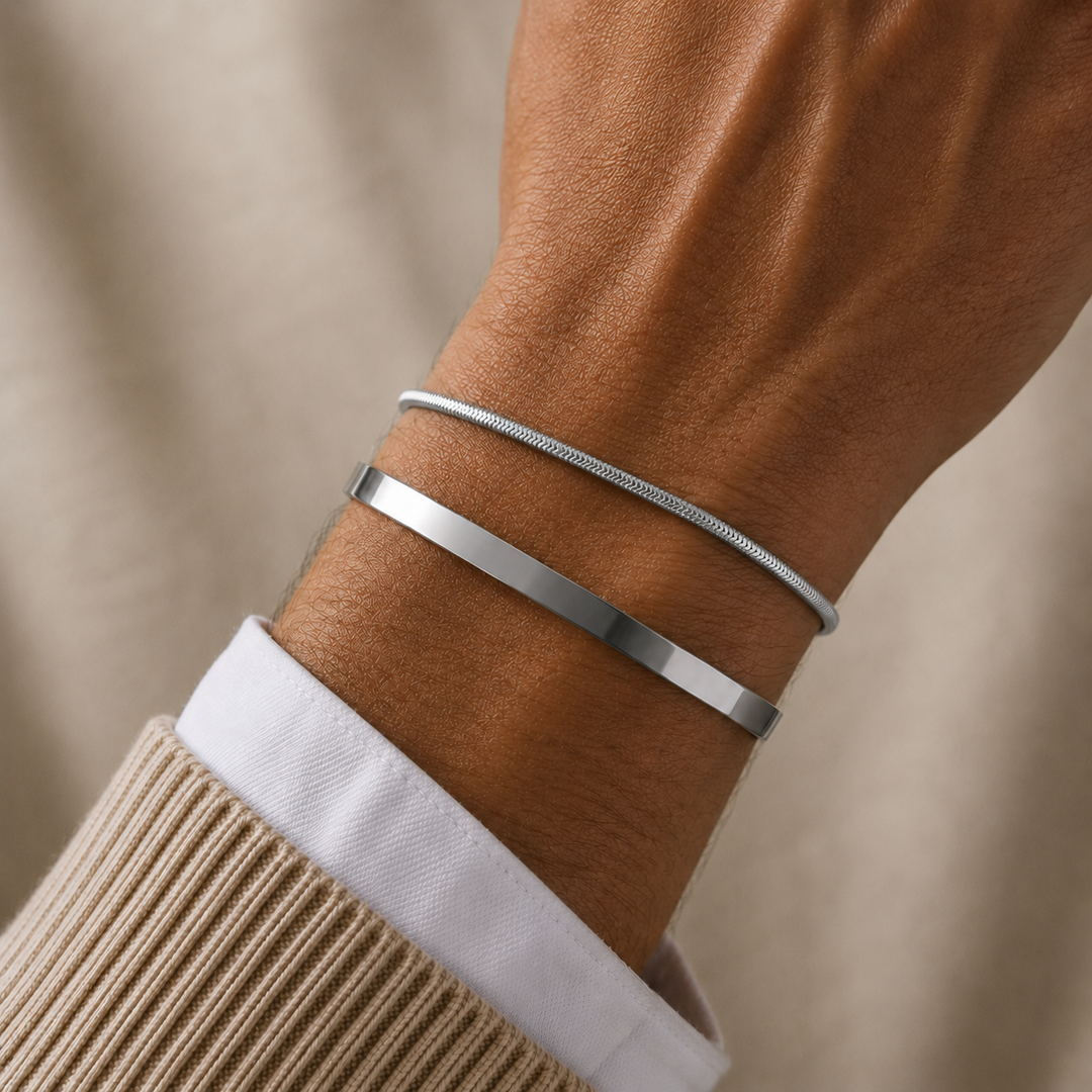 Two slim silver bracelets worn on a person&