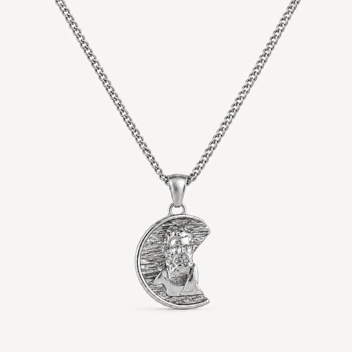 A silver pendant necklace featuring a crescent moon with a detailed portrait of Jesus Christ, suspended from a classic curb chain against a clean white background.