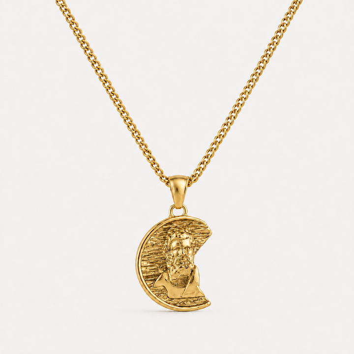 A gold pendant necklace featuring a crescent moon with a detailed portrait of Jesus Christ, suspended from a gold curb chain against a clean white background.