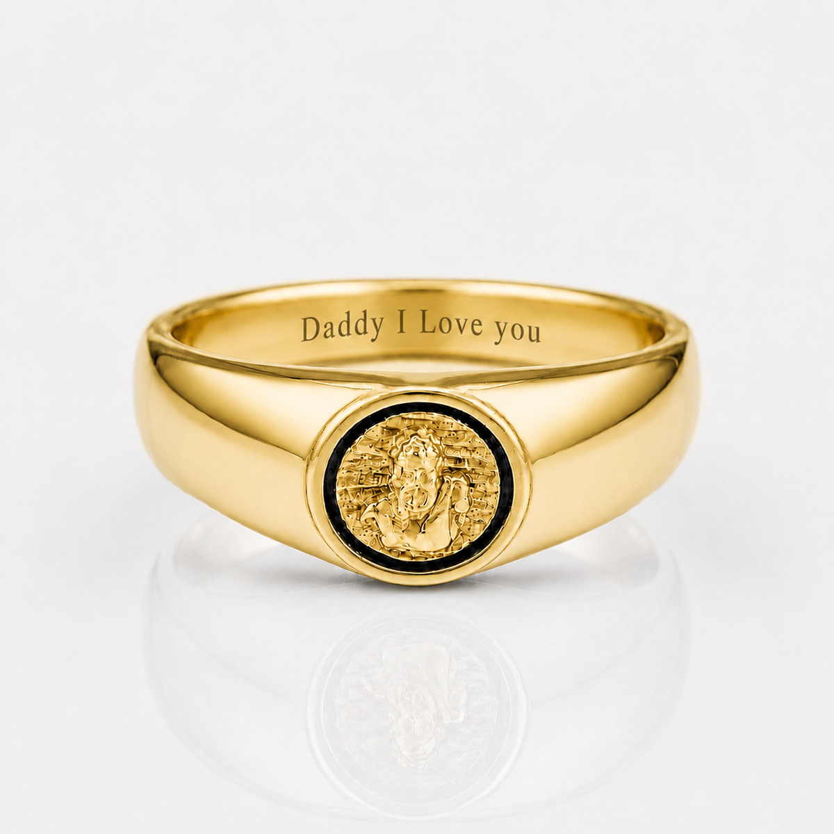 A polished gold signet ring engraved with 'Daddy I Love you' inside the band, featuring a circular gold medallion with a black inlay on the face, set against a clean white background with a soft reflection.