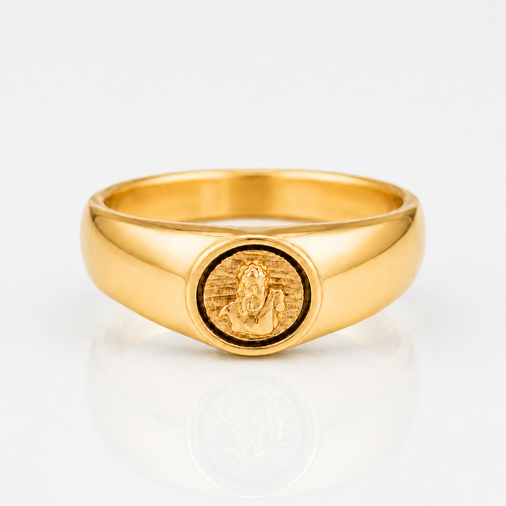 A polished yellow gold signet ring featuring an oval face with an embossed figure, photographed on a clean white reflective surface.