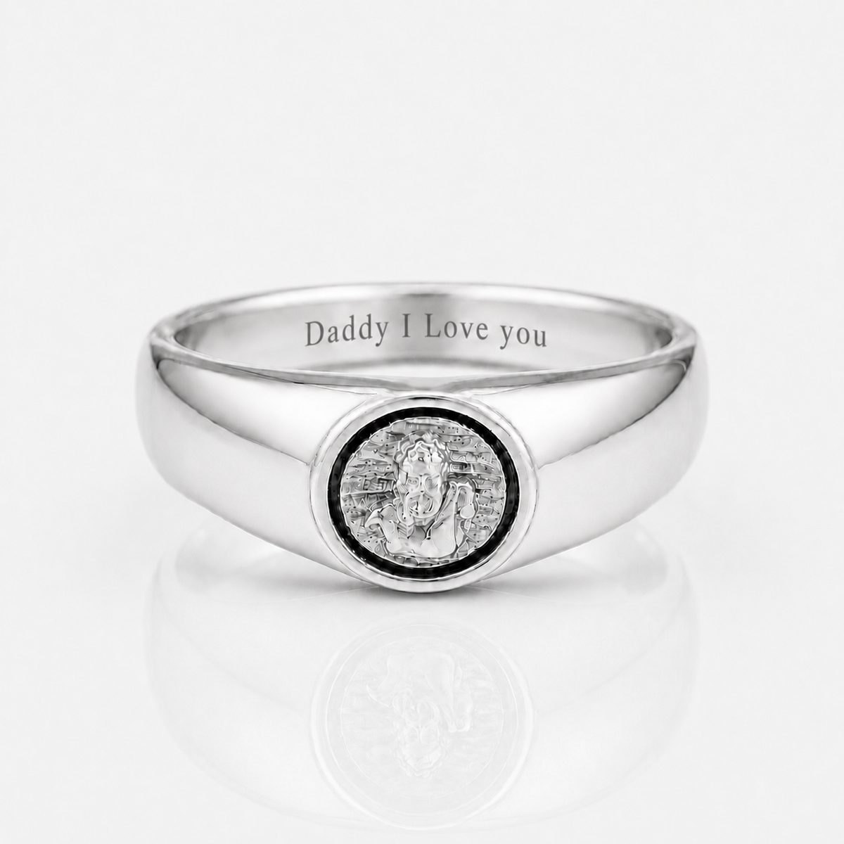A polished silver signet ring engraved with 'Daddy I Love you' on the inside band, featuring a circular medallion with a silver statue of Lord Ganesha in the center, set against a clean white background with a soft reflection.
